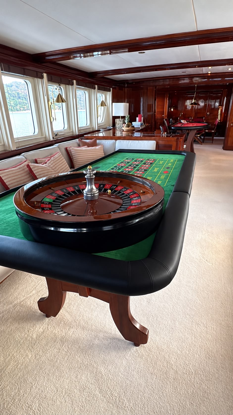 Tavolo roulette nel salone di uno yacht, con il mare visibile dagli oblò